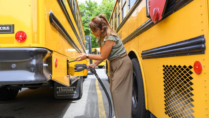A driver plugs in an electric school bus.